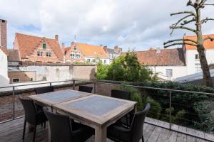 una mesa de madera en un balcón con sillas en Dukes' Apartments Grand Place en Brujas