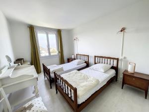 two beds in a room with a sink and a piano at Appartement spacieux près de la plage et commerces, 4 couchages - FR-1-361-433 in Donville-les-Bains