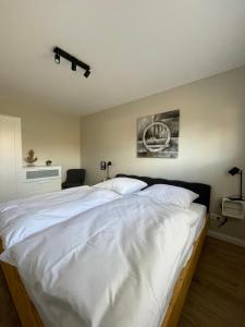 una camera da letto con un grande letto con lenzuola bianche di Ferienwohnung Dünenbutze a Büsum