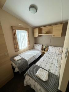 Habitación pequeña con 2 camas y ventana en Lotus Lodge Northumberland, en Felton