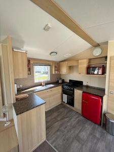 cocina con armarios de madera y nevera roja en Lotus Lodge Northumberland, en Felton