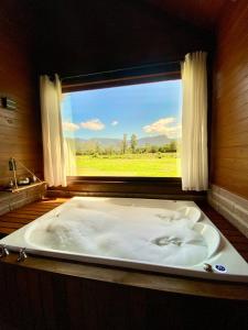 a large bath tub in a room with a window at Cabanas Vale Verde in Praia Grande