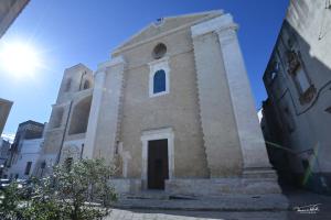 Una pequeña iglesia de piedra con el sol detrás. en B&B CASAVACANZE CHIESA MADRE, en Carovigno