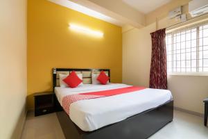 een slaapkamer met een bed met rode kussens en een raam bij OYO Hotel Royal INN Near Nexus Mall Koramangala in Bangalore