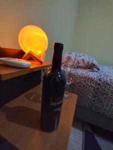 a bottle of wine sitting on a table next to a bed at Suite aconchegante em Cruzeiro in Cruzeiro