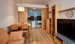 ein Wohnzimmer und eine Küche mit einem Tisch und einem TV in der Unterkunft Sercotel Arrahona Sabadell in Sabadell