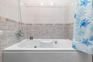 La salle de bains est pourvue d'une baignoire blanche et d'un rideau de douche bleu. dans l'établissement Жк Millennium Park,на Главной площади страны., à Astana 22 autres photos