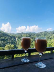 two wine glasses sitting on a table with a view at Minthu Homestay in Ella