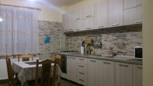 a kitchen with white cabinets and a sink and a table at Pensiunea Zece Brazi Cheia in Măneciu