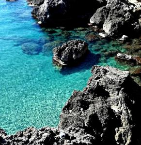 um corpo de água com pedras e água azul em B&B Giostell em Marina di Camerota
