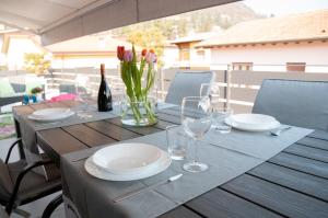 een houten tafel met borden, wijnglazen en bloemen bij Casa Nicho Salo' in Salò