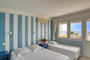 2 camas en una habitación con una pared a rayas en Cap Nègre Hôtel, en Le Lavandou