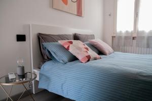een bed met roze en blauwe kussens en een tafel bij Casa Nicho Salo' in Salò