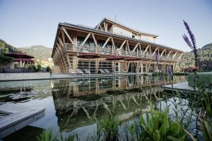 a large building with a reflection in the water at HUBERTUS Mountain Refugio Allgäu in Balderschwang