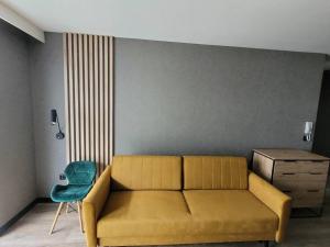a living room with a yellow couch and a blue chair at Apartament z ogródkiem nad morzem in Gdańsk