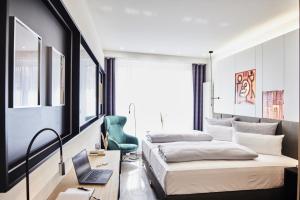 a bedroom with two beds and a desk with a laptop at Design- und Kunsthotel München in Munich