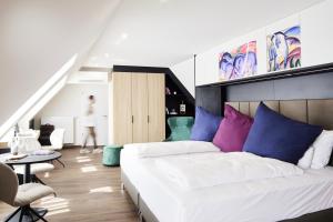 ein Schlafzimmer mit einem großen Bett mit blauen und violetten Kissen in der Unterkunft Design- und Kunsthotel München in München