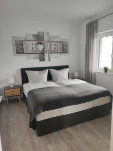Schlafzimmer mit einem schwarzen und weißen Bett und einem Fenster in der Unterkunft Ferienhaus Luna am schönen Harkebrügger See mit Kamin in Barßel