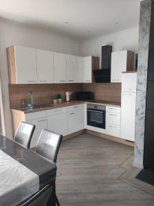 a kitchen with white cabinets and a table and chairs at Ferienhaus Luna am schönen Harkebrügger See mit Kamin und Sauna in Barßel