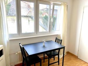 a dining room table with two chairs and two windows at City Apartment - close to town - by PA in Luzern