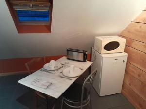 einen kleinen weißen Tisch mit einer Mikrowelle und einem Computer darauf in der Unterkunft La cabane: Chambre double, salle de bain privée in Vatan