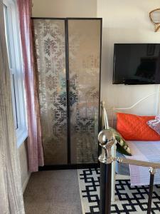 um quarto com uma porta de vidro e uma cama com uma televisão em "The Quirky" Seafront Apartment em Eastbourne