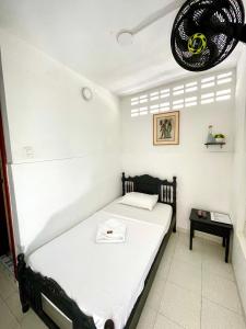 a bedroom with a white bed with a black headboard at Hotel Mangata in Cartagena de Indias