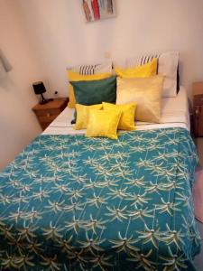 a large bed with yellow and blue sheets and pillows at La villa du cocotier in Sali Nianiaral