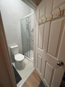 baño con aseo y ducha y puerta en Private Self Contained Studio In The Heart Of Golders Green en Londres