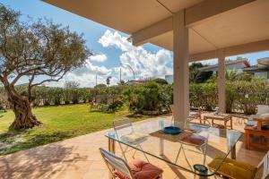 un patio con tavolo, sedie e un albero di Villa Arrecifes a Fertilia