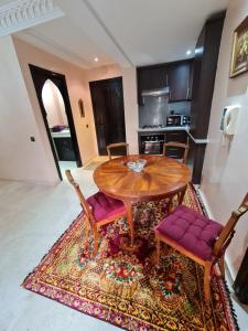une cuisine avec une table et des chaises en bois sur un tapis dans l'établissement Luxury apartment 2 in the heart of Gueliz, Wifi, Pool, à Marrakech