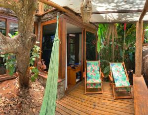 un porche de una casa con dos sillas y un árbol en Casas D'Água Doce - Casa Lotus, en Ilhabela
