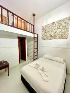 a bedroom with a bed with white sheets and a ladder at Hotel Mangata in Cartagena de Indias