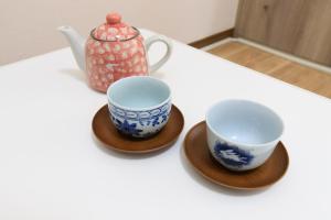 dos tazas y una tetera sentada en una mesa en Rooms天神 02, en Fukuoka
