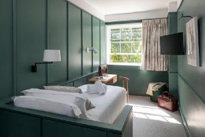 a green bedroom with a bed and a window at The Goodenough Hotel London in London