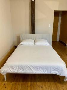 uma cama branca com duas almofadas num quarto em Appartement de 50m2 au centre de Cusset em Cusset