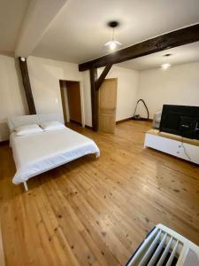 um quarto com uma cama branca e piso em madeira em Appartement de 50m2 au centre de Cusset em Cusset