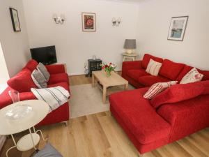 uma sala de estar com dois sofás vermelhos e uma mesa em Ty Coets, Morfa Farm em Llantwit Major
