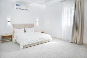 a white bedroom with a bed and a window at Luxury and Modern Hotel Apartments in Mudhainib in Medina