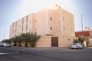 a large building with cars parked in front of it at Luxury and Modern Apartments in Mudhainib in Al Madinah