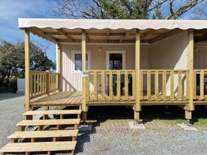 a house with a porch with a roof at Camping Les P'tites Maisons dans la Prairie in Sallertaine