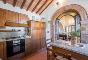 a kitchen with wooden cabinets and a stone archway at Casale Rosennano - Padronale in Rosennano