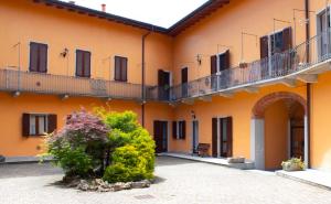 un edificio arancione con balcone e cespuglio di Il Monastero a Castelletto sopra Ticino