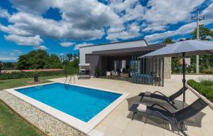 a swimming pool with two chairs and an umbrella next to a house at Villa Dual in Sveti Petar u Šumi