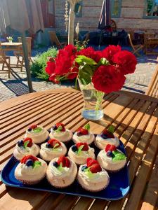 een dienblad met cupcakes op een tafel met een vaas met bloemen bij Killegården på Kivik in Kivik