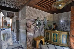 a woman sitting at a desk with a laptop in a room at Riad Semlalia in Fez