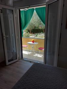 Schlafzimmer mit einer Tür, die auf eine Terrasse mit einem Tisch führt in der Unterkunft Soba Ana in Cres