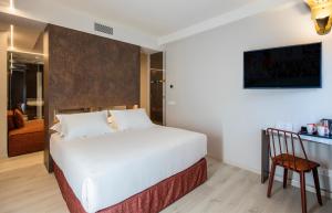 a bedroom with a white bed and a chair at Axel Hotel San Sebastián - Adults Only in Donostia-San Sebastián
