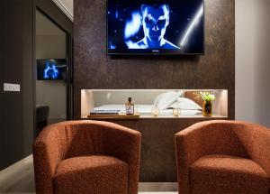 a room with two chairs and a tv on the wall at Axel Hotel San Sebastián - Adults Only in Donostia-San Sebastián