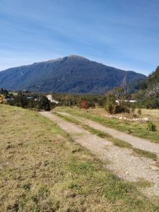 un chemin de terre avec une montagne en arrière-plan dans l'établissement CABAÑA PARCELA VISTA HERMOSA, à Puerto Aisén